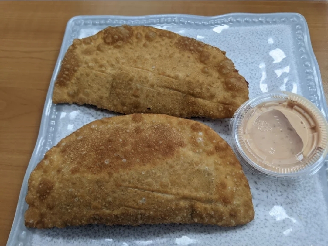 Two golden-fried empanadas with chipotle dipping sauce