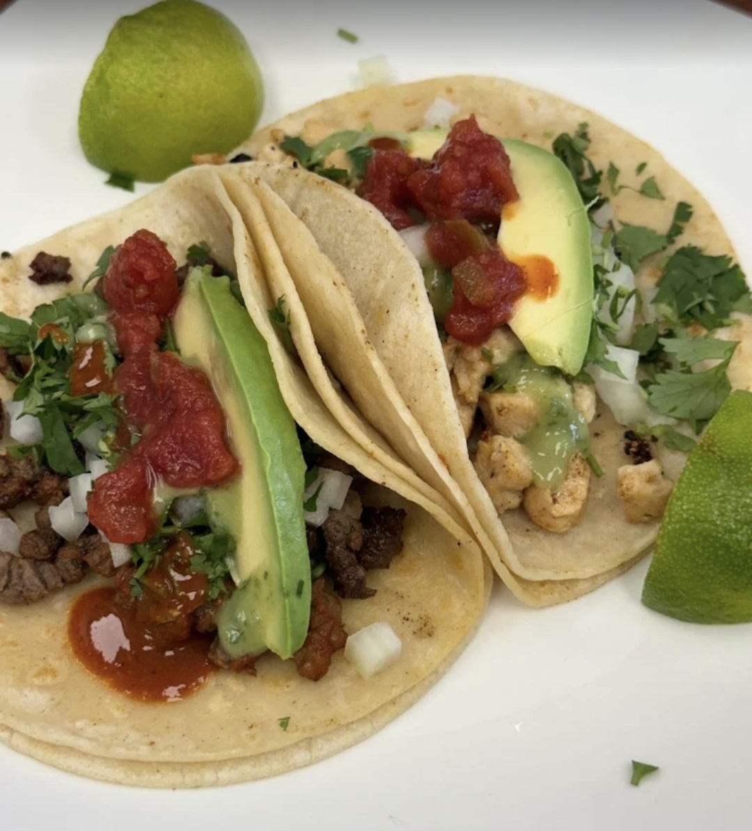 Two street tacos — beef with salsa and chicken with avocado and lime