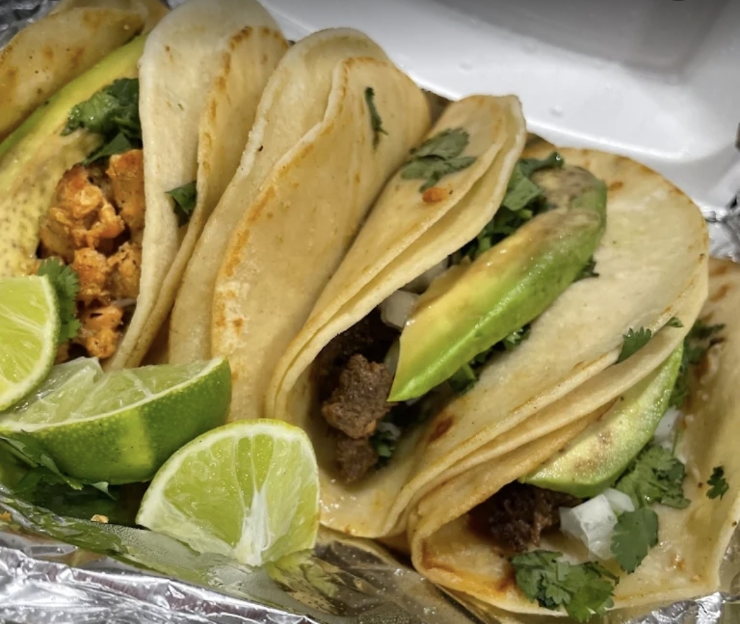 Variety of street tacos — al pastor, asada and chicken with avocado and lime