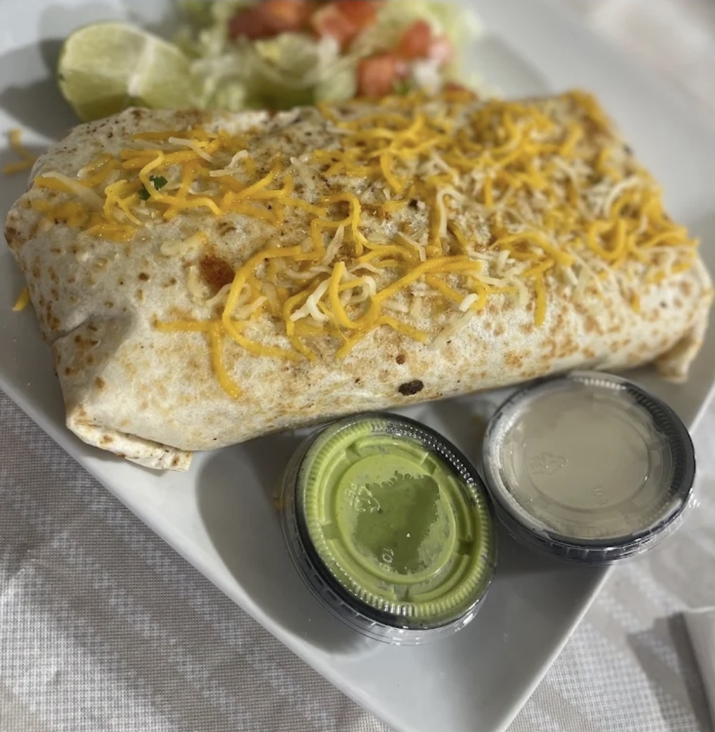 Oversized cheese-topped burrito with salsa verde and crema