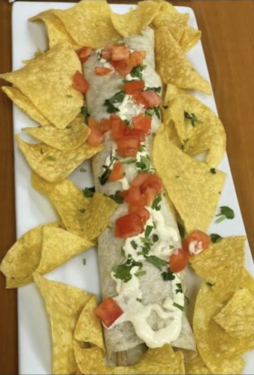 Burrito topped with crema, pico and cilantro, served with chips