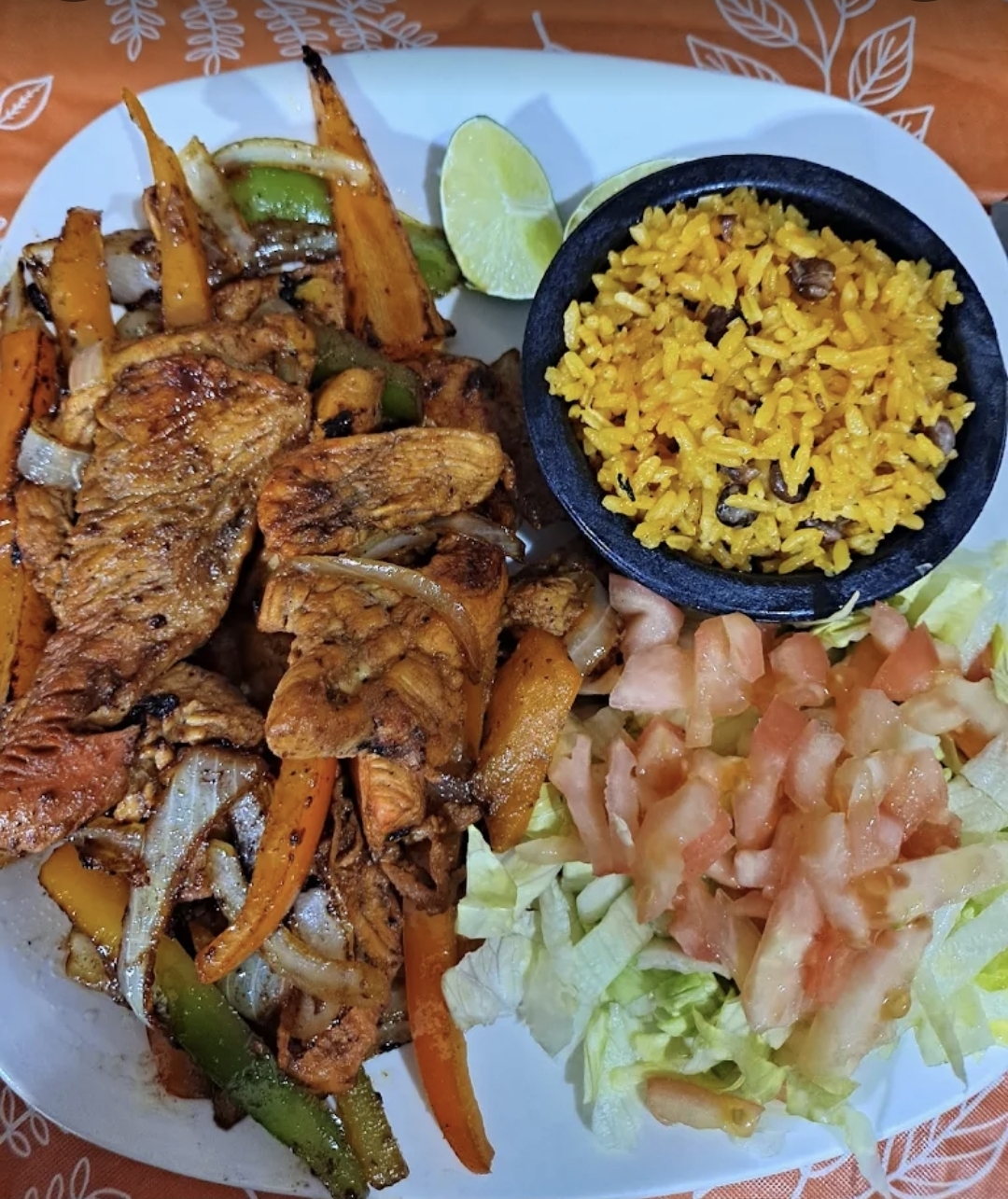 Sizzling chicken fajitas with peppers, onions, yellow rice and salad